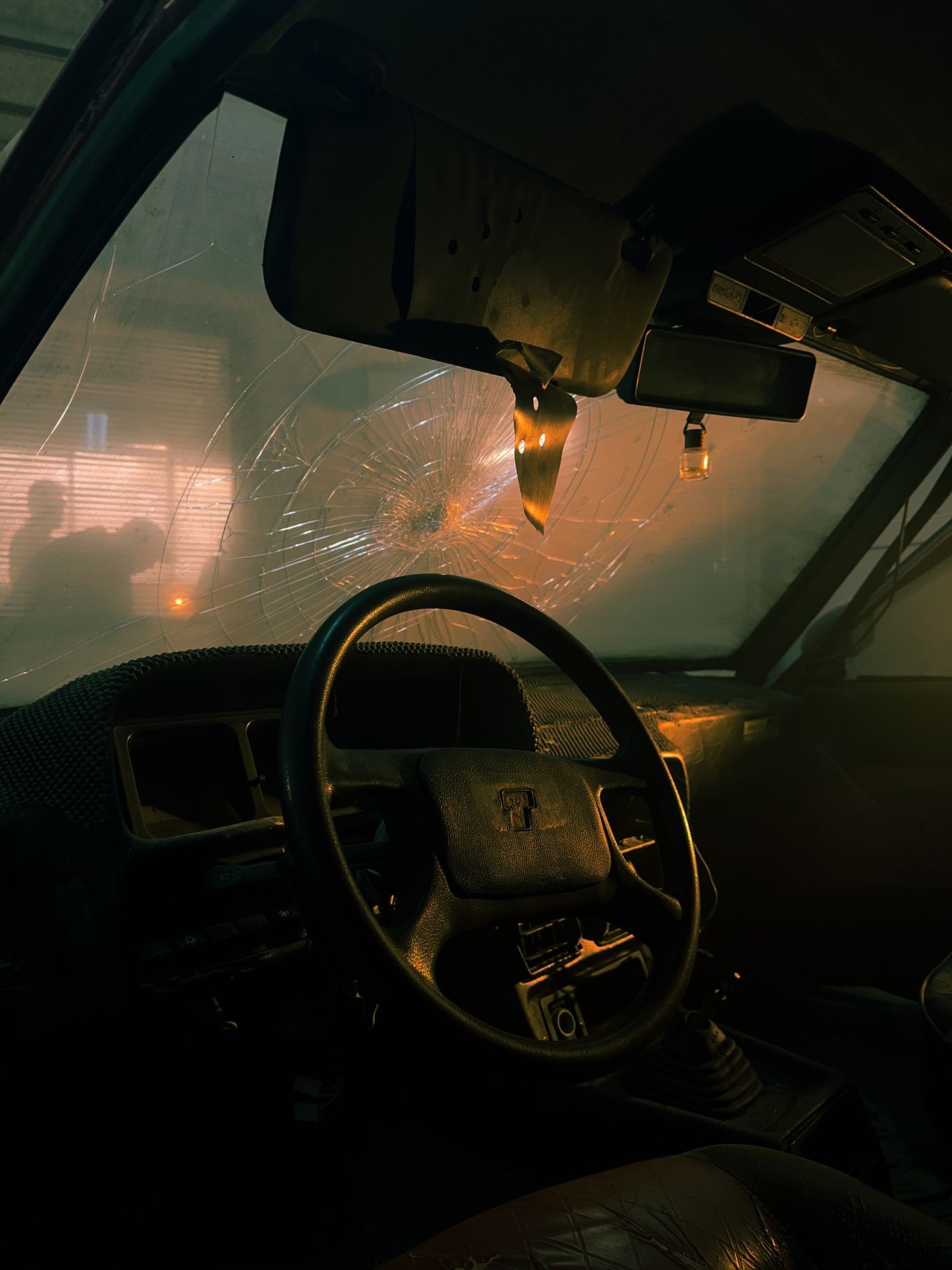Interior of a car with a cracked windshield awaiting repair at night