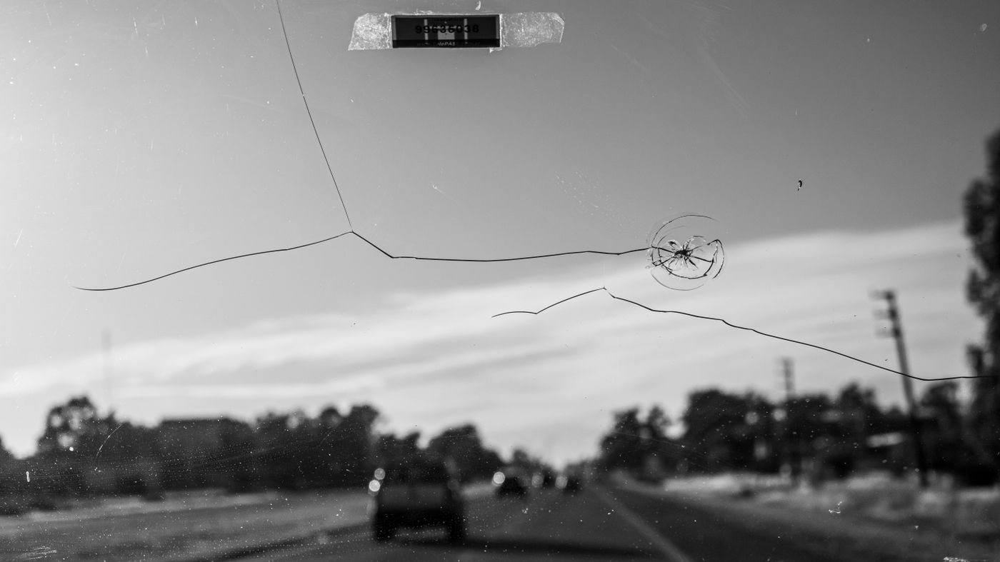 A long crack and stone chip spreading across a windshield seen from the driver's seat