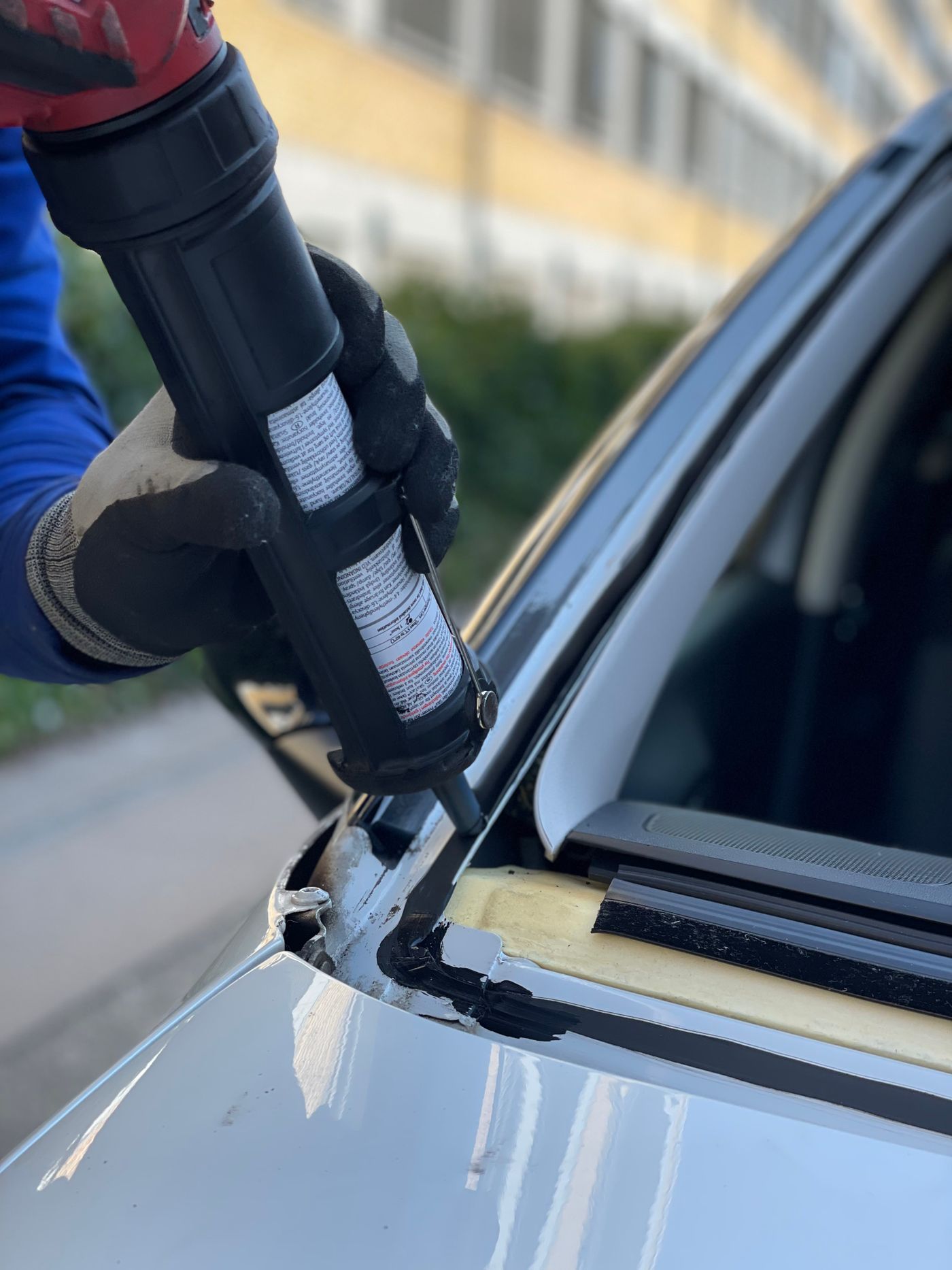 Technician applying urethane adhesive along a windshield edge